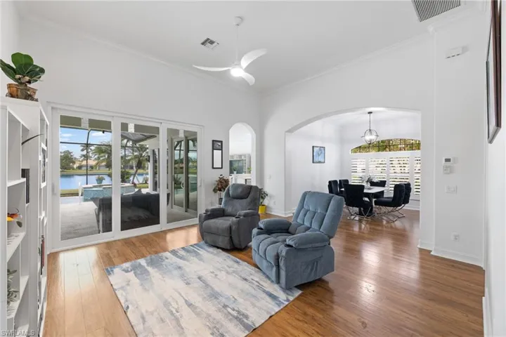 Living room with ceiling fan with notable chandelier, hardwood / wood-style ceramic tile flooring, and arched walkways