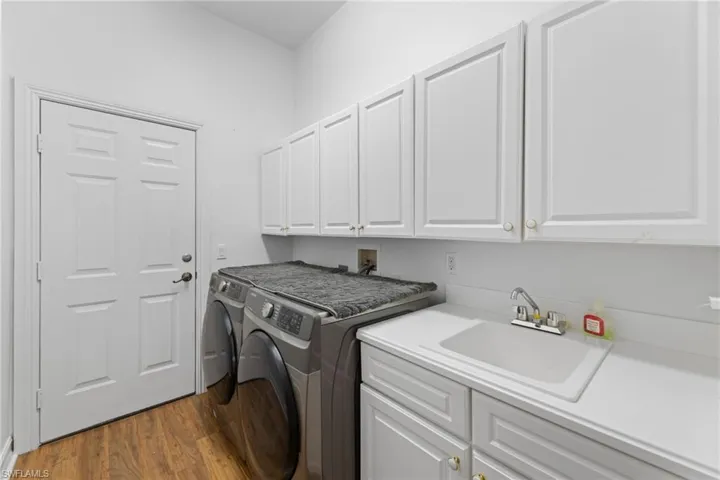 Laundry room with washer and dryer, sink and cabinet space, wood finished ceramic tile floors