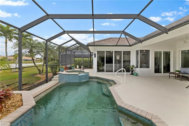 View of pool with screened in lanai enclosure, a pool with connected hot tub, and a covered patio
