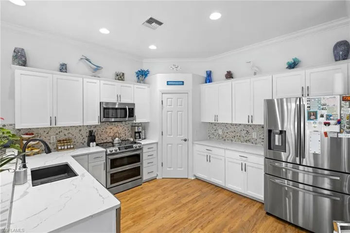 Updated Kitchen featuring light wood ceramic tile floors, a sink, appliances with stainless steel finishes, and white cabinetry