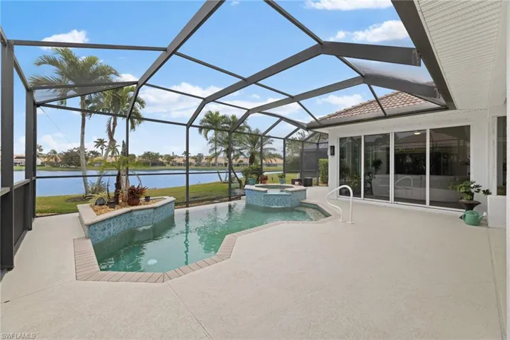 View of swimming pool with a patio, a water view, a pool with connected hot tub, and a lanai