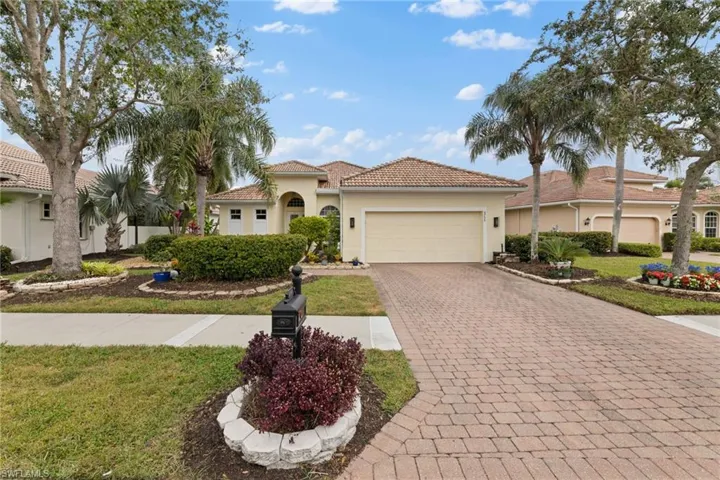 View of front facade featuring a front lawn, a tiled roof, stucco siding, decorative paver driveway, and a 2 car garage