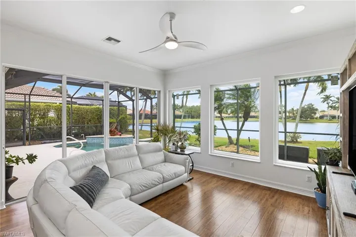 Sunroom like living with baseboards, ornamental molding, a beautiful water view, and wood-type ceramic tile flooring