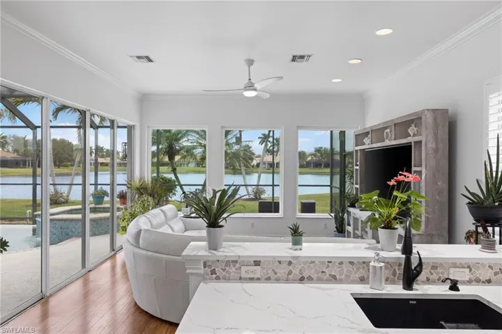 Sunroom like living area with wood finished ceramic tile floors, and ornamental molding