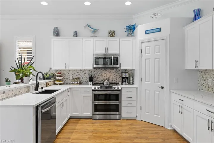 Fully updated Kitchen featuring sit up bar, a sink, stainless steel appliances, light wood-style ceramic floors floors, and white cabinetry