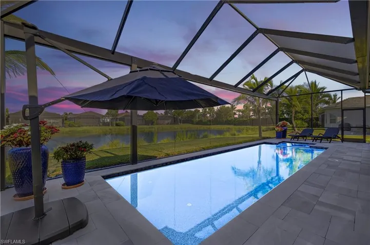 View of swimming pool with a lawn, glass enclosure, a sunroom, and a water view