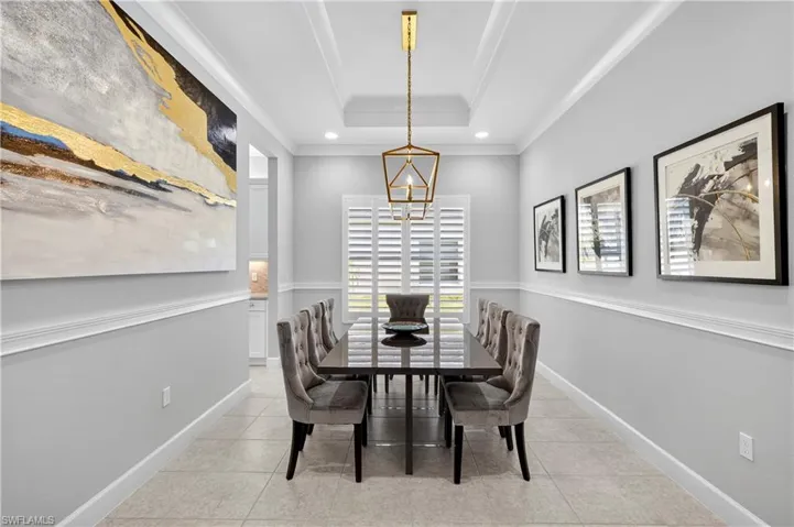 Dining space with light tile patterned flooring, a tray ceiling, and recessed lighting