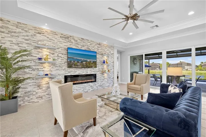 Living room featuring tile patterned floors, a fireplace, ceiling fan, crown molding, and recessed lighting