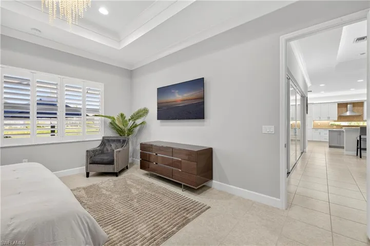 Bedroom with recessed lighting, a tray ceiling, ornamental molding, light tile patterned floors, and a chandelier