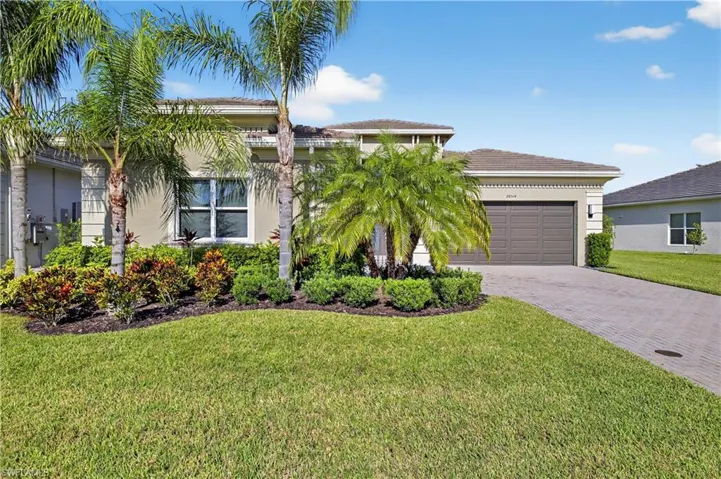 View of front of property featuring decorative driveway, stucco siding, a front lawn, an attached garage, and a tiled roof