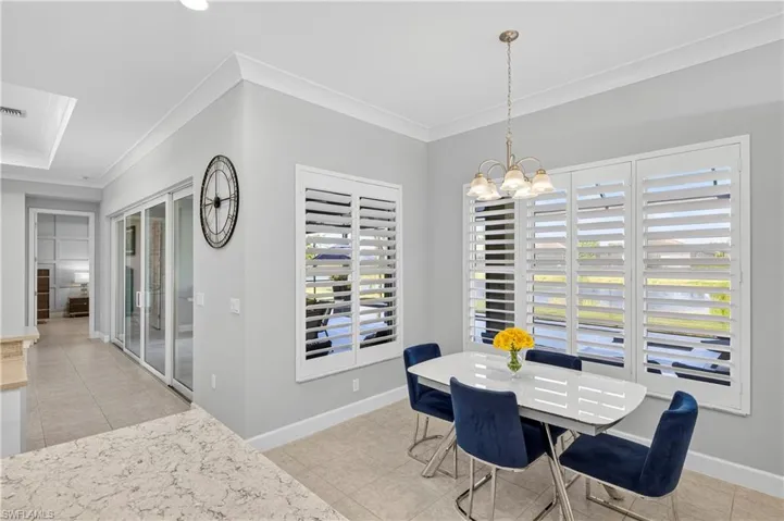 Dining area with light tile patterned floors, ornamental molding, and a chandelier