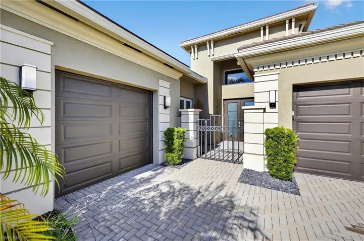 View of front of house featuring stucco siding, decorative driveway, a gate, and a garage