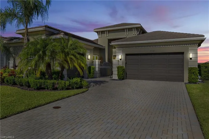 View of front facade with a garage, decorative driveway, a gate, and stucco siding