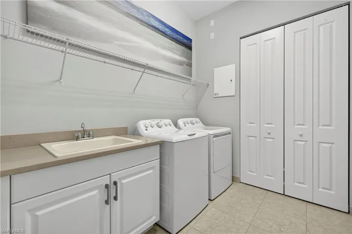 Washroom with separate washer and dryer, light tile patterned flooring, and cabinet space