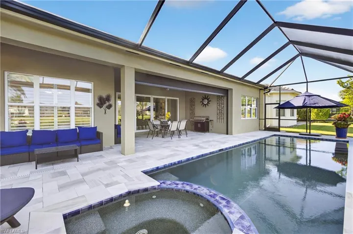 View of swimming pool featuring a sunroom, a pool with connected hot tub, a patio area, and outdoor lounge area