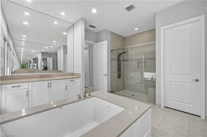 Bathroom with a stall shower, vanity, recessed lighting, and light tile patterned flooring
