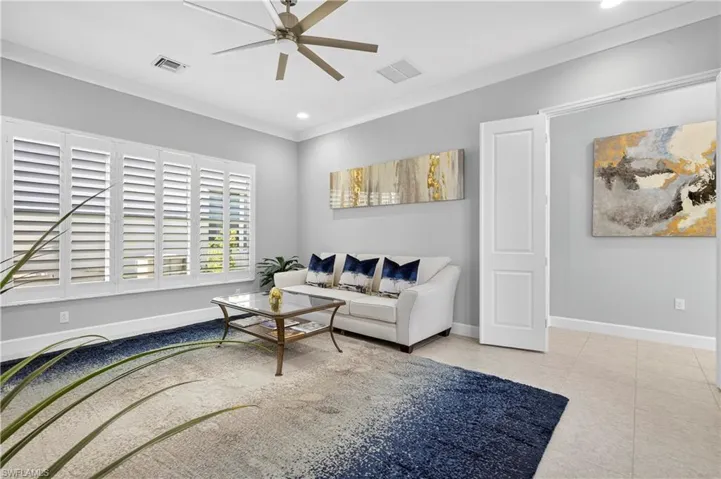 Tiled living area with ornamental molding, recessed lighting, and ceiling fan