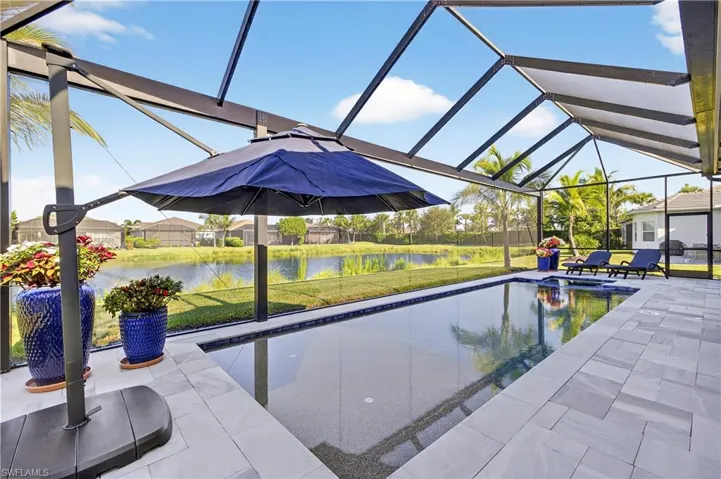 View of pool featuring a yard, a sunroom, glass enclosure, and a pool with connected hot tub