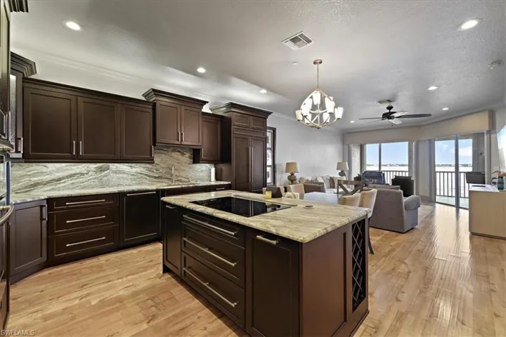 Kitchen with a chandelier, decorative light fixtures, dark brown cabinetry, a kitchen island, and decorative backsplash
