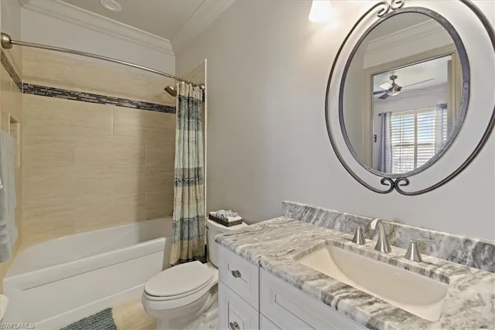 Bathroom with crown molding, shower / tub combo with curtain, vanity, and a ceiling fan
