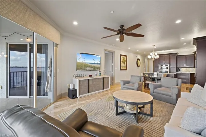 Living room with ornamental molding, a chandelier, a ceiling fan, light wood-style flooring, and recessed lighting