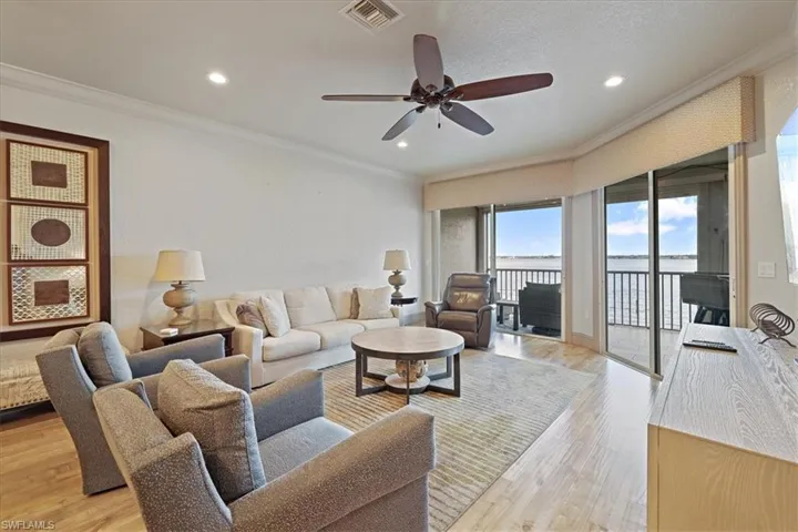 Living area with crown molding, light wood-type flooring, a ceiling fan, a water view, and recessed lighting