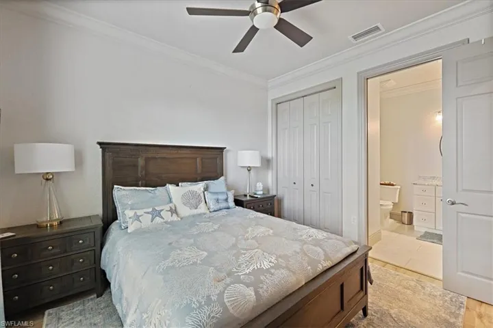 Bedroom featuring ornamental molding, ensuite bathroom, a closet, and a ceiling fan