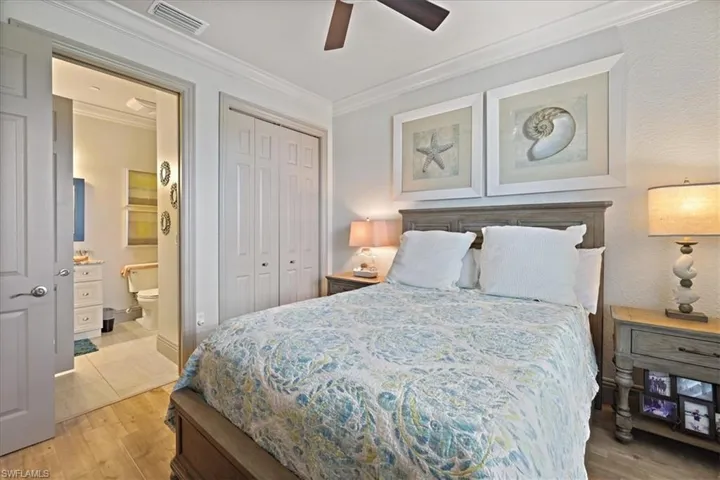 Bedroom with ornamental molding, light wood-style floors, a closet, ensuite bath, and ceiling fan