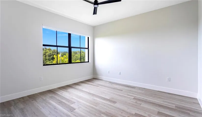 Unfurnished room featuring baseboards, light wood-style flooring, and a ceiling fan