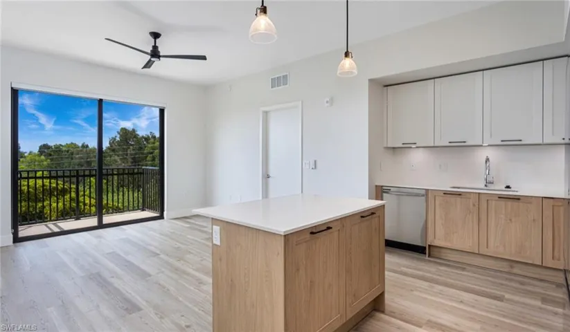 Kitchen featuring tasteful backsplash, visible vents, light wood-style flooring, stainless steel dishwasher, and a sink