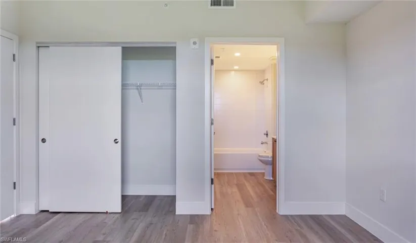Unfurnished bedroom featuring a closet, baseboards, and wood finished floors