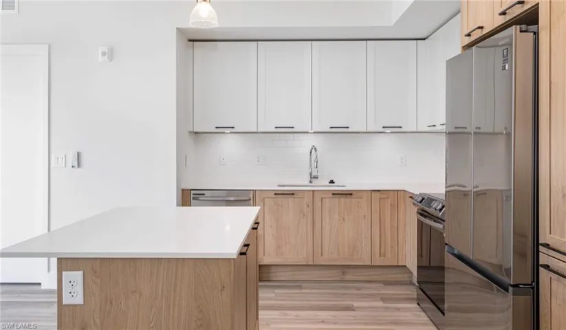 Kitchen with a sink, tasteful backsplash, appliances with stainless steel finishes, and light countertops
