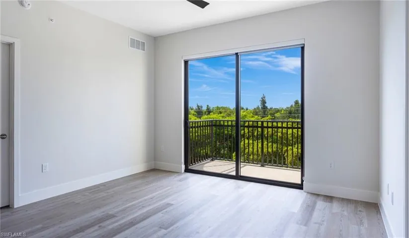 Empty room featuring visible vents, ceiling fan, baseboards, and wood finished floors