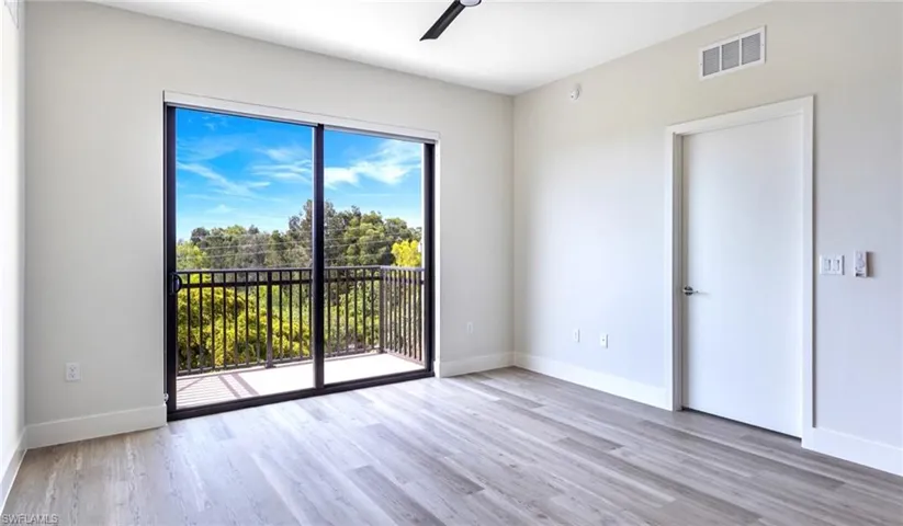 Empty room with ceiling fan, wood finished floors, visible vents, and baseboards