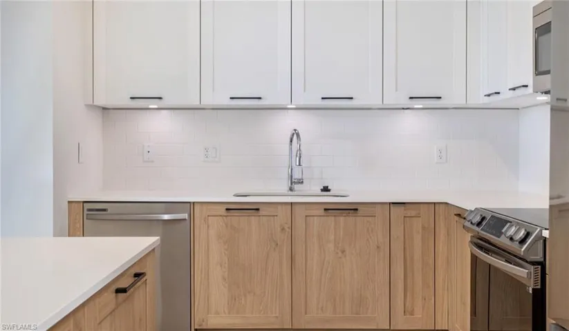 Kitchen featuring a sink, stainless steel appliances, tasteful backsplash, and light countertops