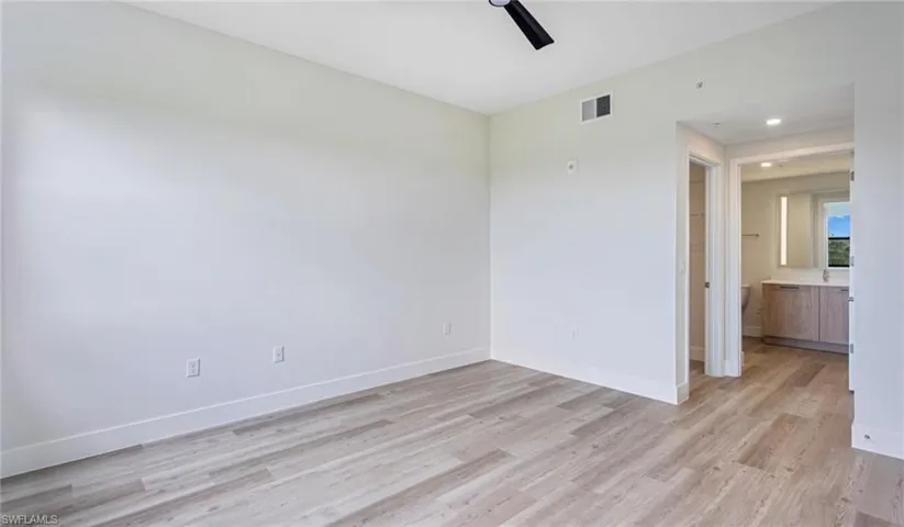 Empty room with visible vents, baseboards, light wood-style floors, and a ceiling fan