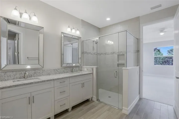 Bathroom with double vanity, wood tiled floors, a stall shower, and recessed lighting