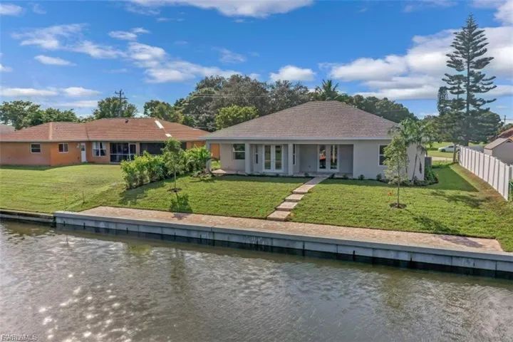 Rear view of property featuring a water view, stucco siding, and a yard
