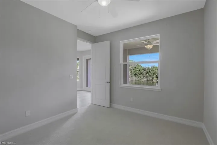 Carpeted empty room featuring baseboards and a ceiling fan