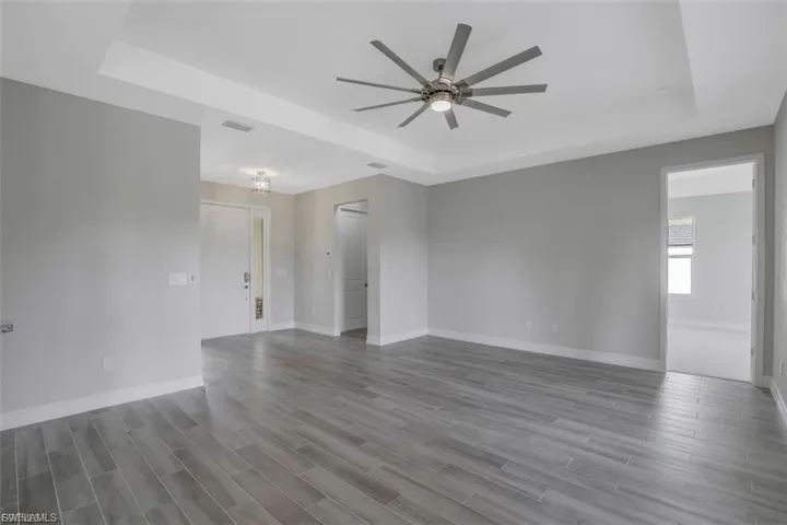 Spare room with a tray ceiling, a ceiling fan, and light wood-style flooring