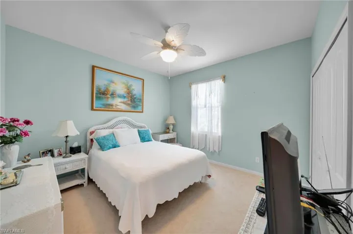 Bedroom featuring light colored carpet, a closet, baseboards, and ceiling fan