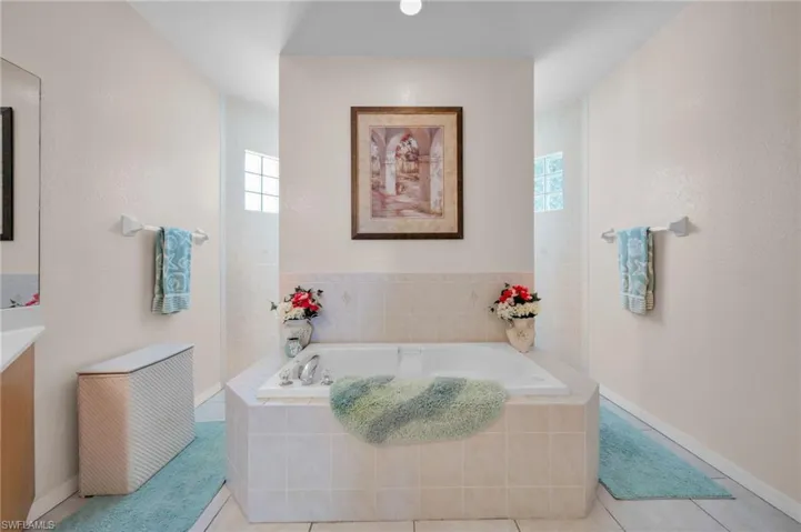 Bathroom featuring a garden tub, vanity, and tile patterned flooring