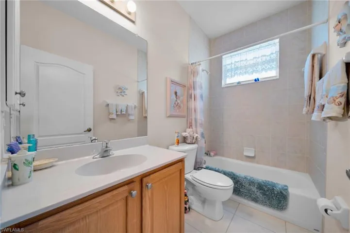 Bathroom featuring tile patterned floors, toilet, shower / tub combo, and vanity