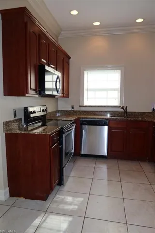 Kitchen featuring wood cabinetry, stainless steel appliances, granite countertops, tile flooring, and recessed lighting