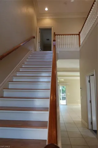 Two-story foyer featuring wood-finish staircase, white risers, and wood handrails