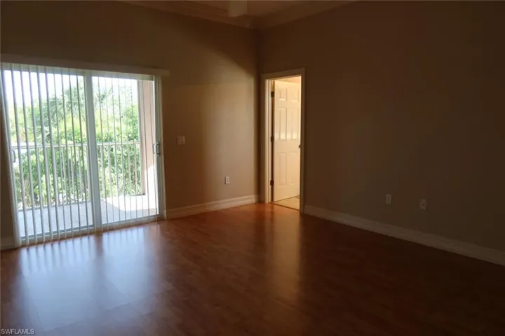 Spacious interior room featuring rich wood-finish flooring, neutral wall tones, and crown molding