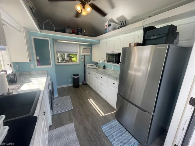 Kitchen with white cabinets, refrigerator, light countertops, dark wood-style flooring, and a ceiling fan