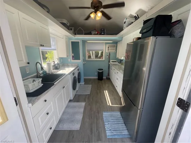 Kitchen featuring white cabinets, refrigerator, light countertops, dark wood finished floors, and ceiling fan