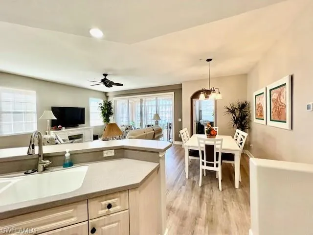 Kitchen featuring a sink, open floor plan, ceiling fan with notable chandelier, decorative light fixtures, and light wood-style floors