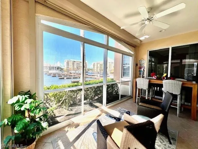 Sunroom with a city view, a water view, tile patterned flooring, and a ceiling fan